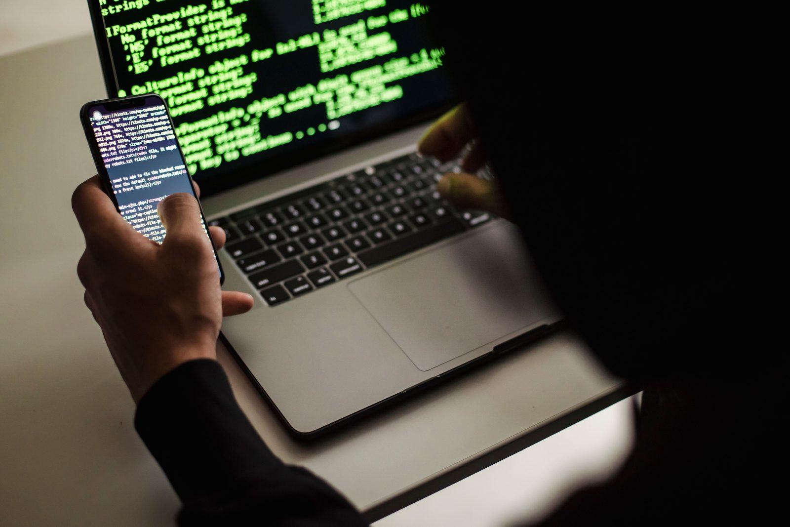 Ontwikkelaar werkt aan beveiligingscode op laptop en smartphone